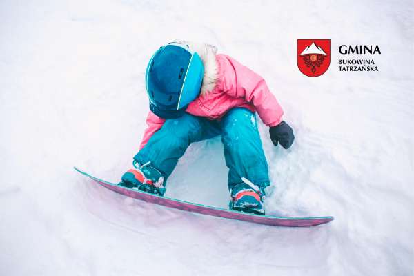 Dziecko na śniegu z ubraną deską snowboardową. 